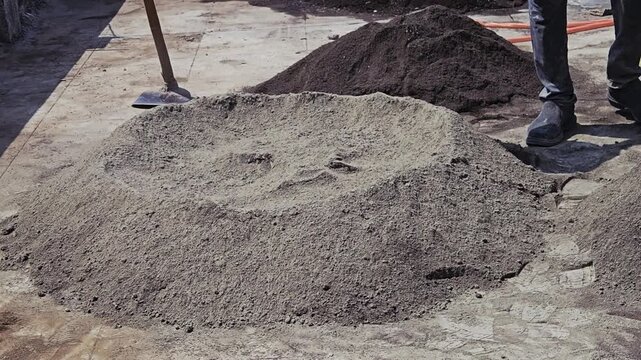 Workers manually mix sand and cement into a uniform dry mix on a clean surface. This traditional hand-mixing technique is ideal for small batches of concrete or mortar before water is finally added.