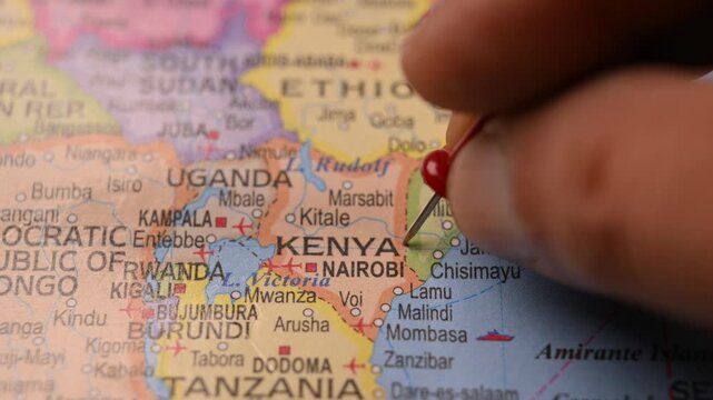 Man Marking Kenya Location with Red Pin on Paper World Map in 4K 60fps Close-Up Travel Concept