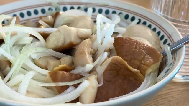 pickled porcini mushrooms with onions Pickled mushroom salad with green onions and butter rotates on a plate.