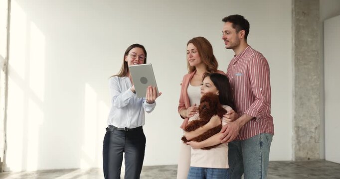 Smiling Caucasian family receiving keys from realtor agent, standing in unfurnished apartment with child daughter and dog. Property purchase, house buying, real estate transactions, tenancy concept