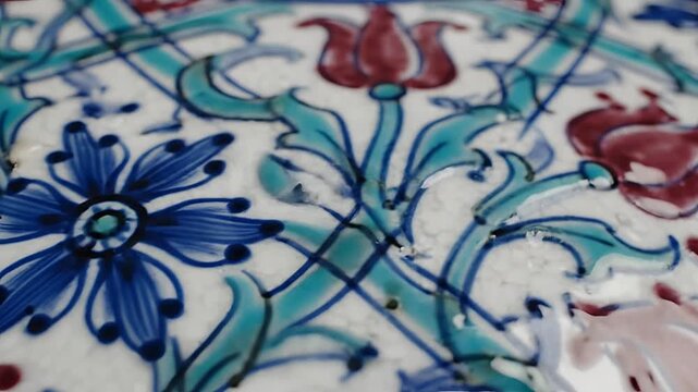 Closeup of intricate floral ceramic tile pattern with blue and red flowers.