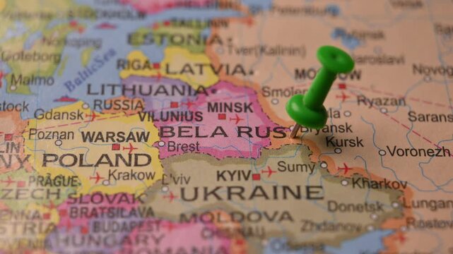 Man Marking Belarus Location with Green Pin on Paper World Map in 4K 60fps Close-Up Travel Concept