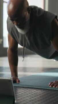 Fitness, push up and black man in gym with tablet for online workout , arm training or wellness. Health, technology and mature male person with tutorial for exercise or practice in sports center.