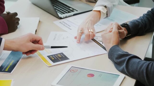 Collaborative Business Meeting of a diverse professional team engaged in a strategic meeting. Hands point to data charts and financial documents. teamwork, corporate planning, and collaborative proble