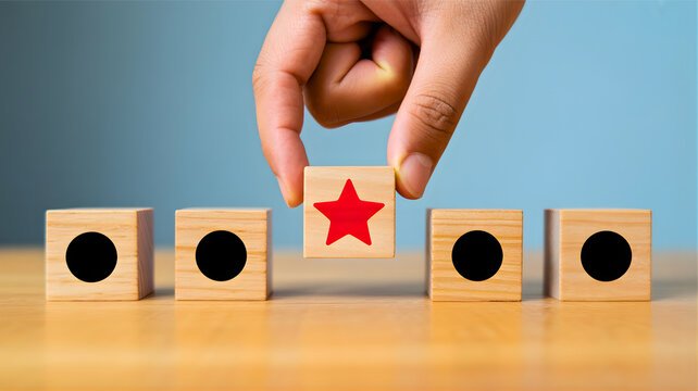 Hand selecting a red star block from a line of wooden blocks on a table, symbolizing achievement, success, and distinction