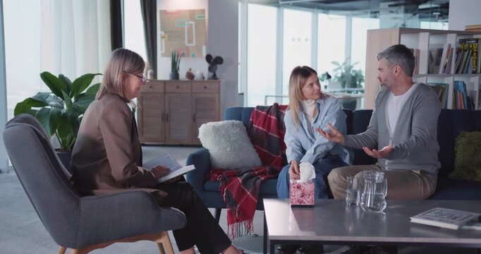 Caucasian family professional therapist listening to married couple complaining their relationship problems conflicting inside apartment. Therapy session. Mental health.
