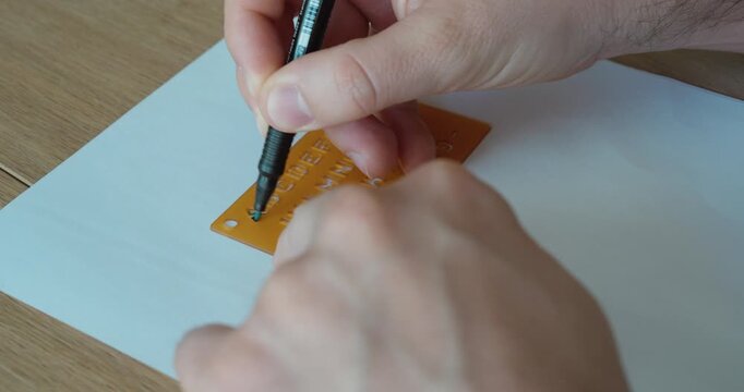 Close-up of a hand using a stencil and pen to draw letters, symbolizing precision, learning, and creativity.