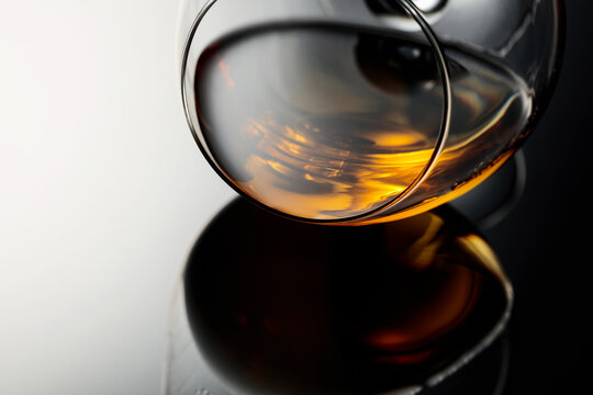 Glass of brandy on a black reflective background.