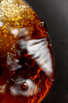 Golden drink is poured into the glass, creating beautiful waves and splashes.
