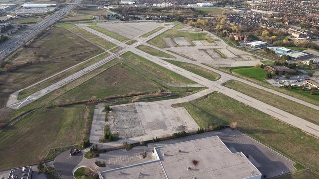 A clockwise aerial drone orbit over the abandoned runways and decommissioned grounds of the former Buttonville Municipal Airport (CYKZ) in Markham, revealing the vast redevelopment site