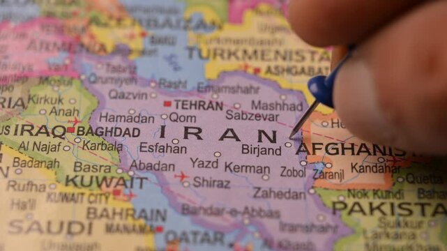 Close-Up World Map Shot Featuring Blue Pin Highlighting Iran Pointed by Hand 4K 60fps