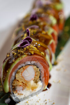 Gourmet sushi roll featuring shrimp tempura, salmon, avocado, and unagi sauce.