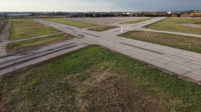 A cinematic aerial drone pull-back and rise over the abandoned runways of the former Buttonville Municipal Airport (CYKZ) in Markham, revealing the Highway 404 corridor and urban development