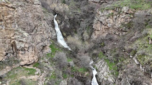 4K aerial drone footage of multi level waterfall in rocky mountain canyon with flowing stream, natural landscape.