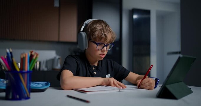Quiet Student Engaged In Homework Activity. Young Male Immersed In Studying With Art Supplies Present