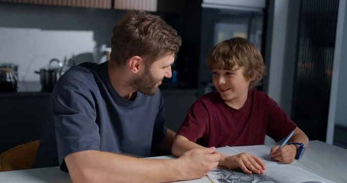 Father Praises Son. Mother And Father Share Proud Moment Encouraging Child During Homework At Dining Table