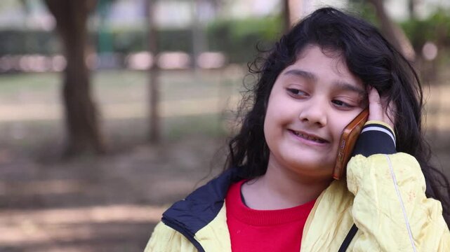 A cheerful Indian child enjoying a phone conversation in a simple rural environment, reflecting innocence, slum village poor india lifestyle, and everyday communication in mountain village life