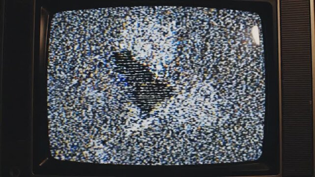 An old television set displays static noise and color bars, representing signal issues or a test pattern on the screen