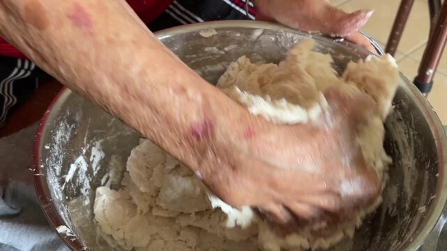 A close-up shot captures hand pressing and kneading a mixture of flour to form a cohesive dough for traditional handmade baozi.