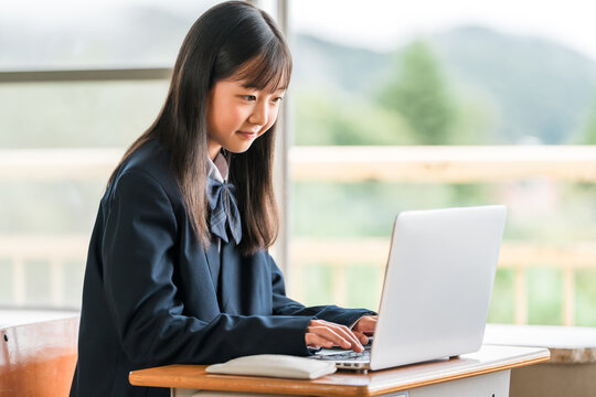 Female middle and high school students in their school uniforms studying using computers.