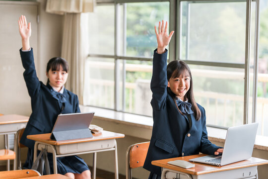 Female middle and high school students in their school uniforms studying using computers.