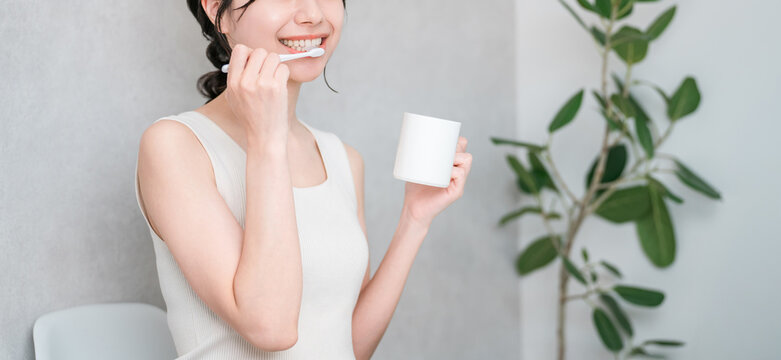 A young Asian woman brushing her teeth (toothbrushing, oral care, dental care)
