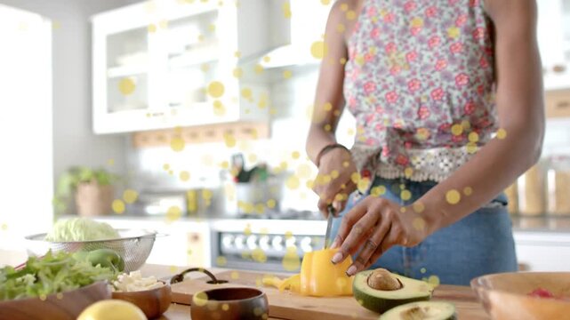 Woman slicing pepper for salad, hands entering frame, camera pulling back, yellow bokeh over veg