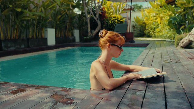Young woman reading book in swimming pool