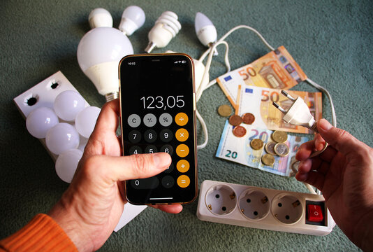 Calculadora m&oacute;vil de energ&iacute;a y money de tel&eacute;fono haciendo contabilidad de gasto en factura luz light con bombillas led energy, ladr&oacute;n conector, dinero en billetes y monedas de gasto energ&eacute;tico
