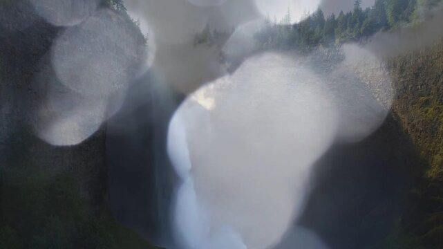 Foreground droplets shifting and merging from spray, slowly revealing waterfall and canyon walls