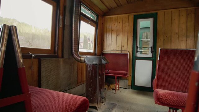 This shows the inside of the Mocanita train carriage with red seats and a wood-burning stove. The steam locomotive travels through the forest in Romania.