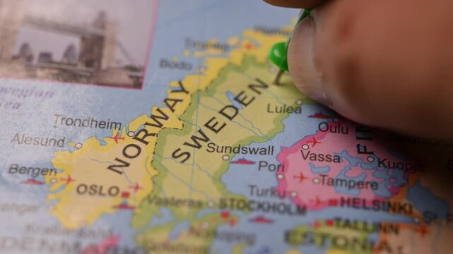 Hand Placing Green Pin on Sweden Location in Paper World Map Travel Concept
