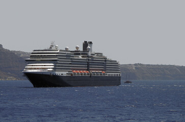Luxury cruiseship cruise ship liner Eurodam anchoring at sea on sunny summer day during Mediterranean Greek Island Santorini caldera cruising with shore and rocky island in background © Tamme Wichmann