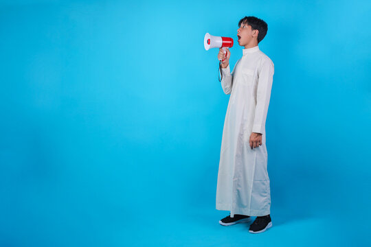 Asian Muslim Boy Shouting Into Megaphone From Side View For Ramadan Announcement