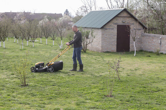 Man Mowing Lawn in Rural Backyard &ndash; Countryside Living and Outdoor Chores Lifestyle