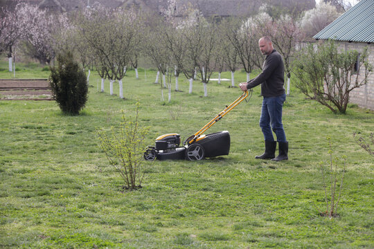 Man Mowing Lawn in Rural Backyard &ndash; Countryside Living and Outdoor Chores Lifestyle