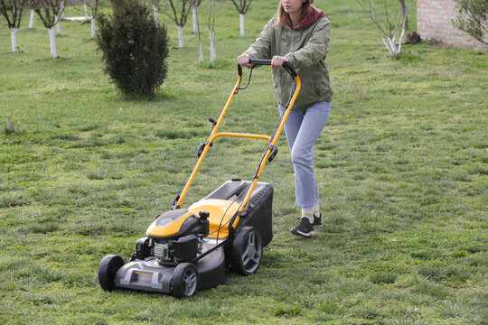 Woman Mowing Lawn in Rural Backyard &ndash; Countryside Living and Outdoor Chores Lifestyle