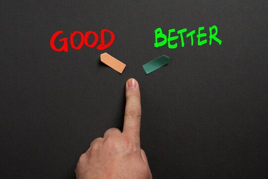 Hand pointing between good and better options illustrating decision making, improvement, evaluation and choosing the best alternative.