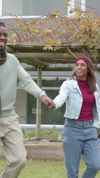 Vertical video: Couple entering left frame and walking under pergola, holding hands for real estate