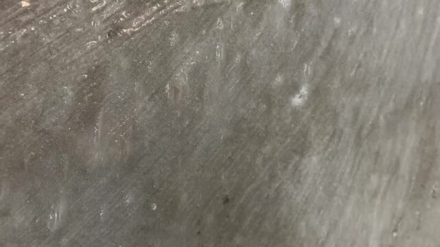 White ethereal smoke, vapor, or steam dissipating in a slow, gentle abstract motion over a dark, textured gray stone or concrete background with a subtle shimmer