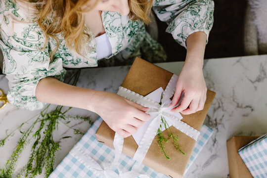 Woman wrapping rustic gift with white ribbon