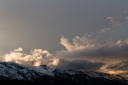 Storm clouds gathering over snowy mountain range at dusk