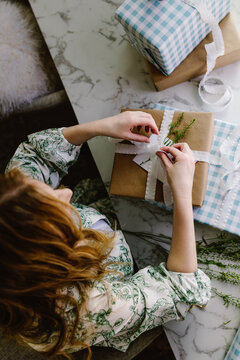 Woman wrapping rustic holiday gifts at table