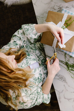 Woman wrapping rustic gift on marble table