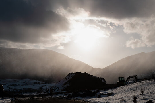 Winter sunlight breaking through storm clouds over construction sight
