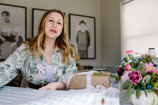 Woman wrapping gift at home with flowers