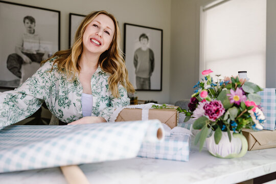 Smiling woman wrapping gifts in bright modern home