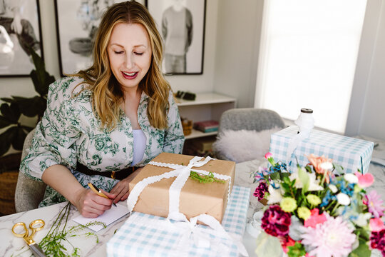 Woman wrapping gift at bright home workspace