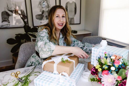 Woman wrapping pastel gifts in bright home