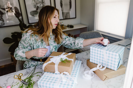 Woman wrapping pastel gingham gift boxes